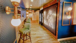 Un pasillo con una zona de bar, una instalación de luces de neón y una escalera.