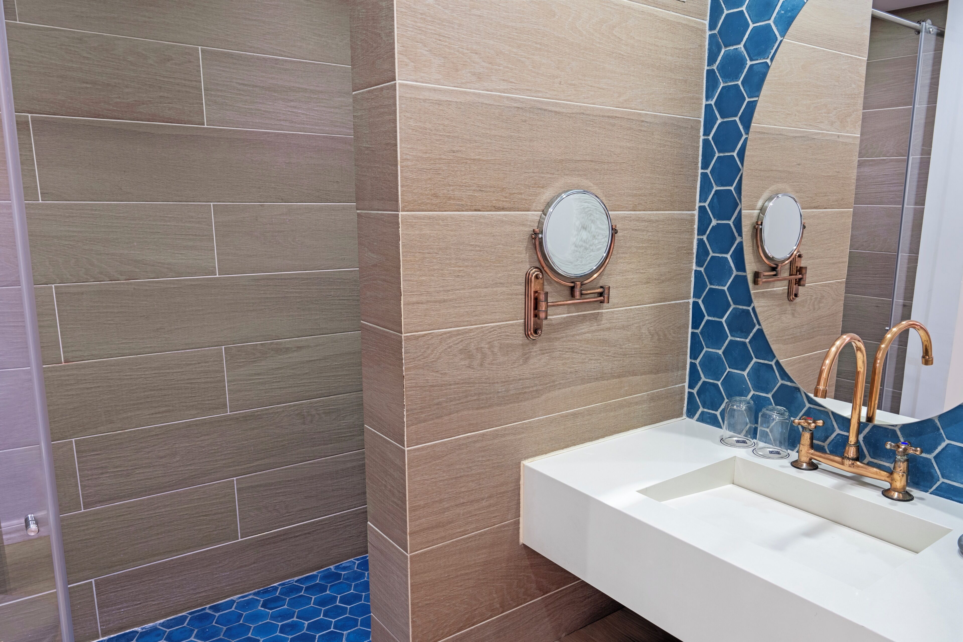 A bathroom with a white sink, copper faucets, and two round mirrors mounted on the wall.