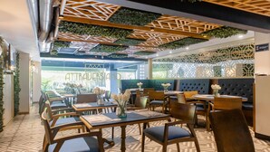 Un restaurante con mesas y sillas de madera, piso estampado y una pared verde con un letrero que dice ATTRALBERSIOM.COM.