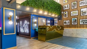 Un área de recepción con una pared azul, suelo de madera y una pared verde con fotografías.