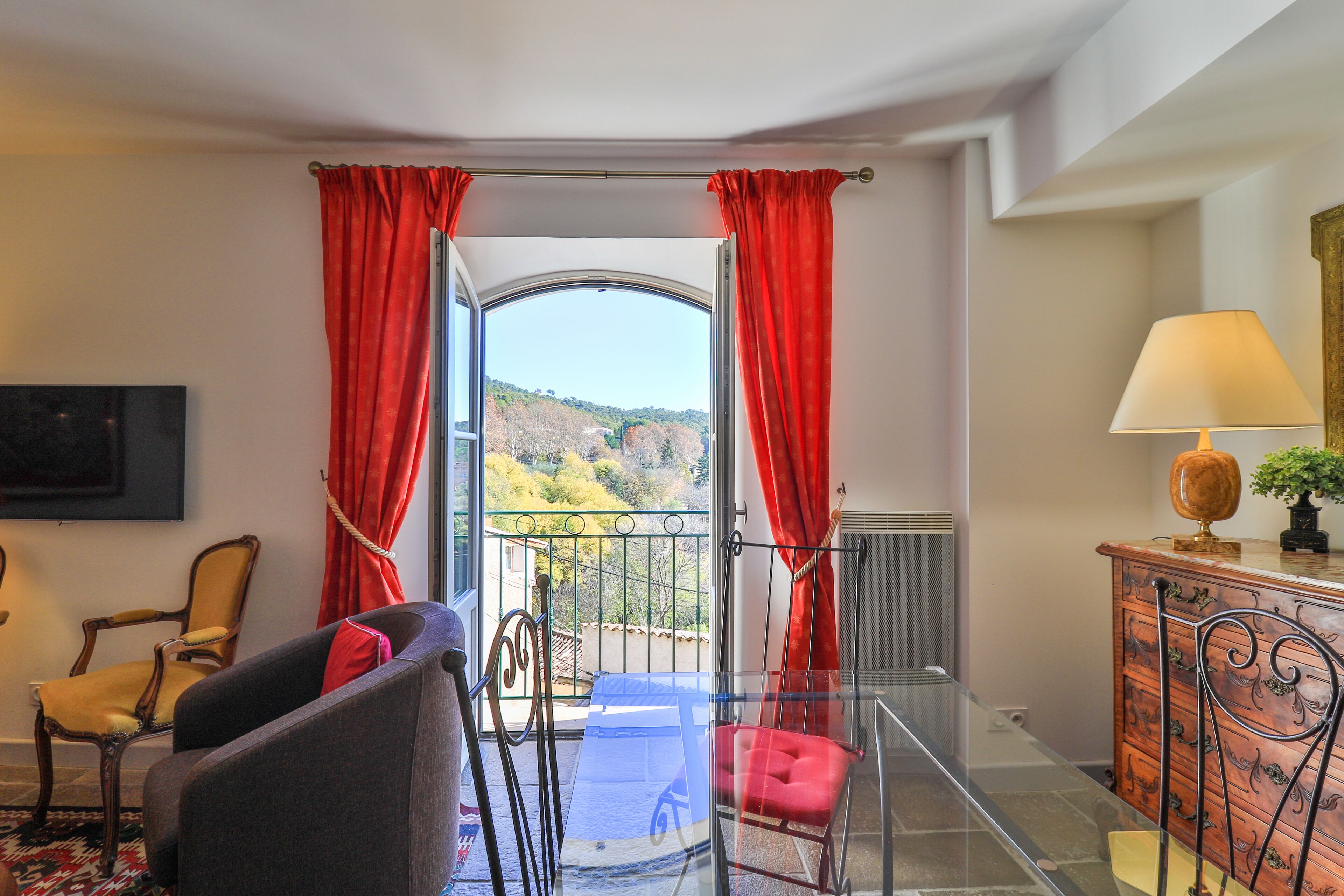 Une pièce avec un balcon, une chaise, un canapé, une lampe et une vue sur l’extérieur.