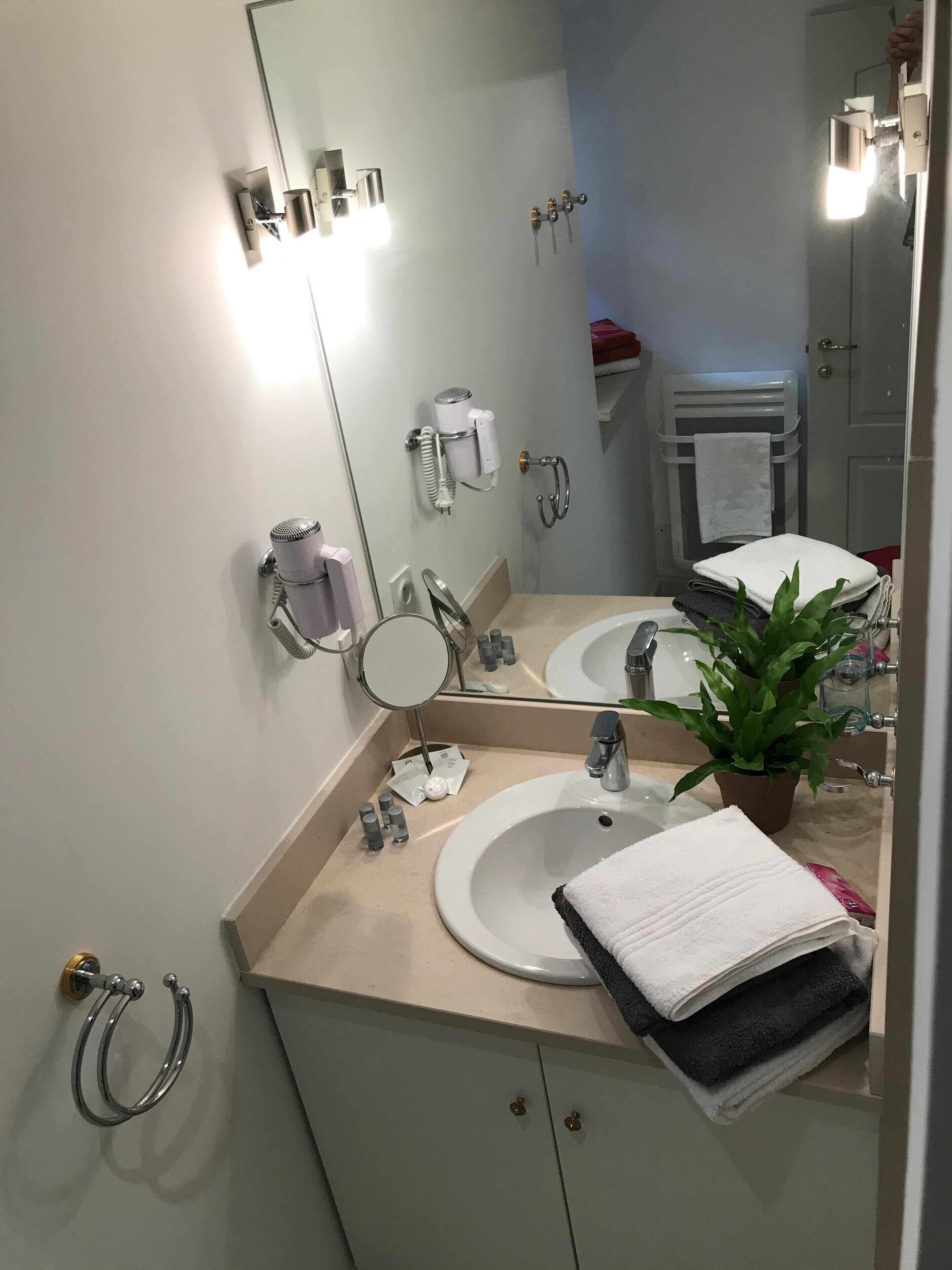 Ein modernes Badezimmer mit zwei Waschbecken, einem großen Spiegel, einem Föhn und einem Handtuchhalter.