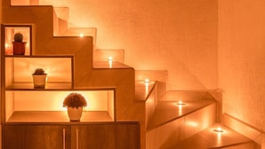 Eine Treppe mit eingebauten Regalen und einem Schrank, die jeweils von einer einzelnen Kerze beleuchtet wird.