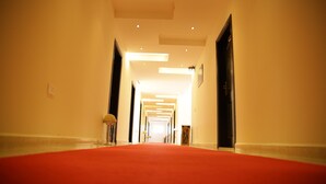 A hotel corridor with a red carpet, recessed lighting, and doors on both sides. - Kalaa Resort (Arnoun)