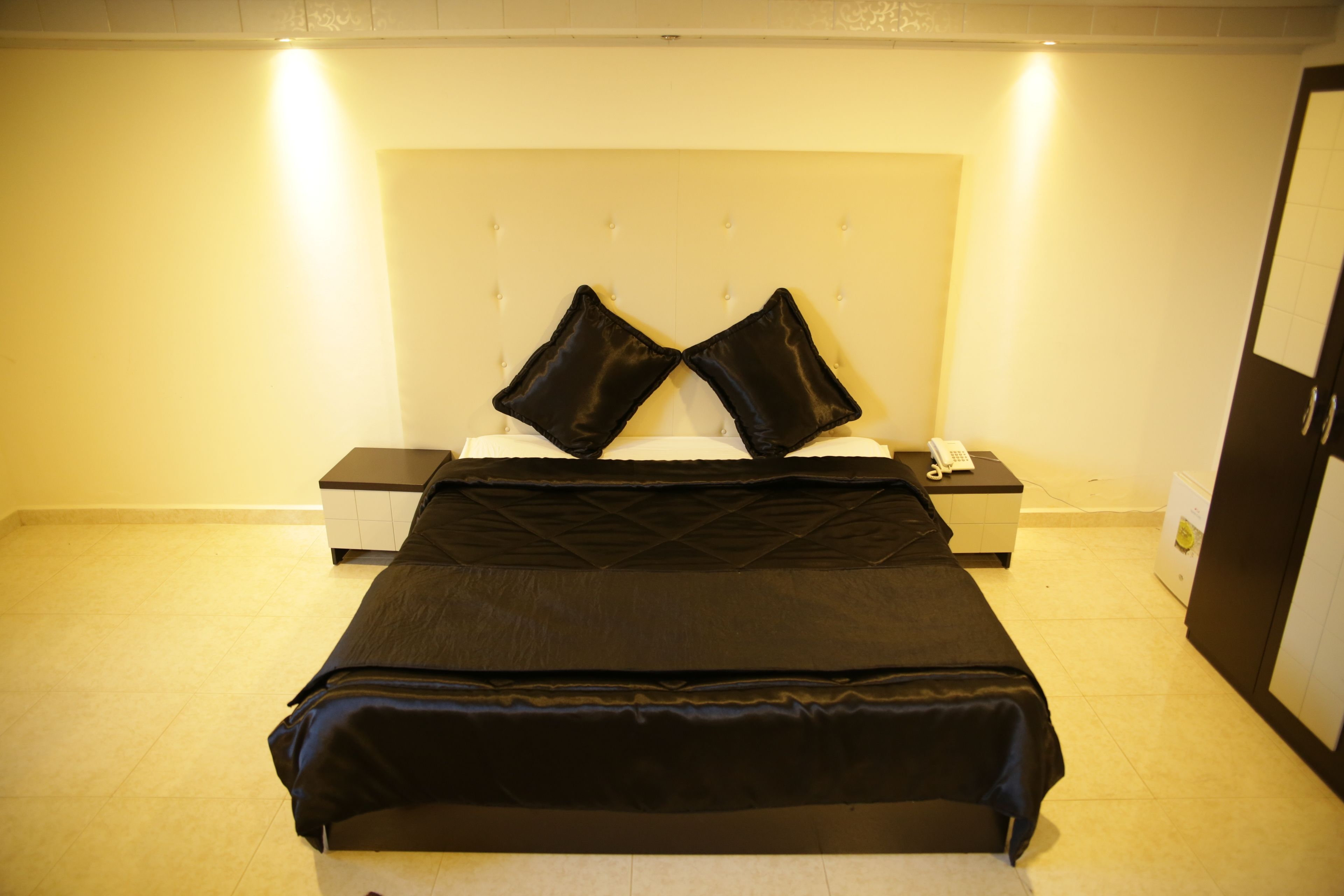 Una habitación de hotel con una cama, una mesita de noche y un armario.