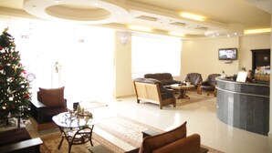 A modern hotel lobby with a reception desk, seating area, and a Christmas tree. - Kalaa Resort (Arnoun)