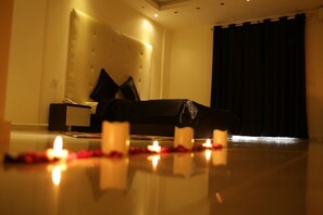 Une pièce faiblement éclairée, avec un lit, une table de chevet et un rideau.