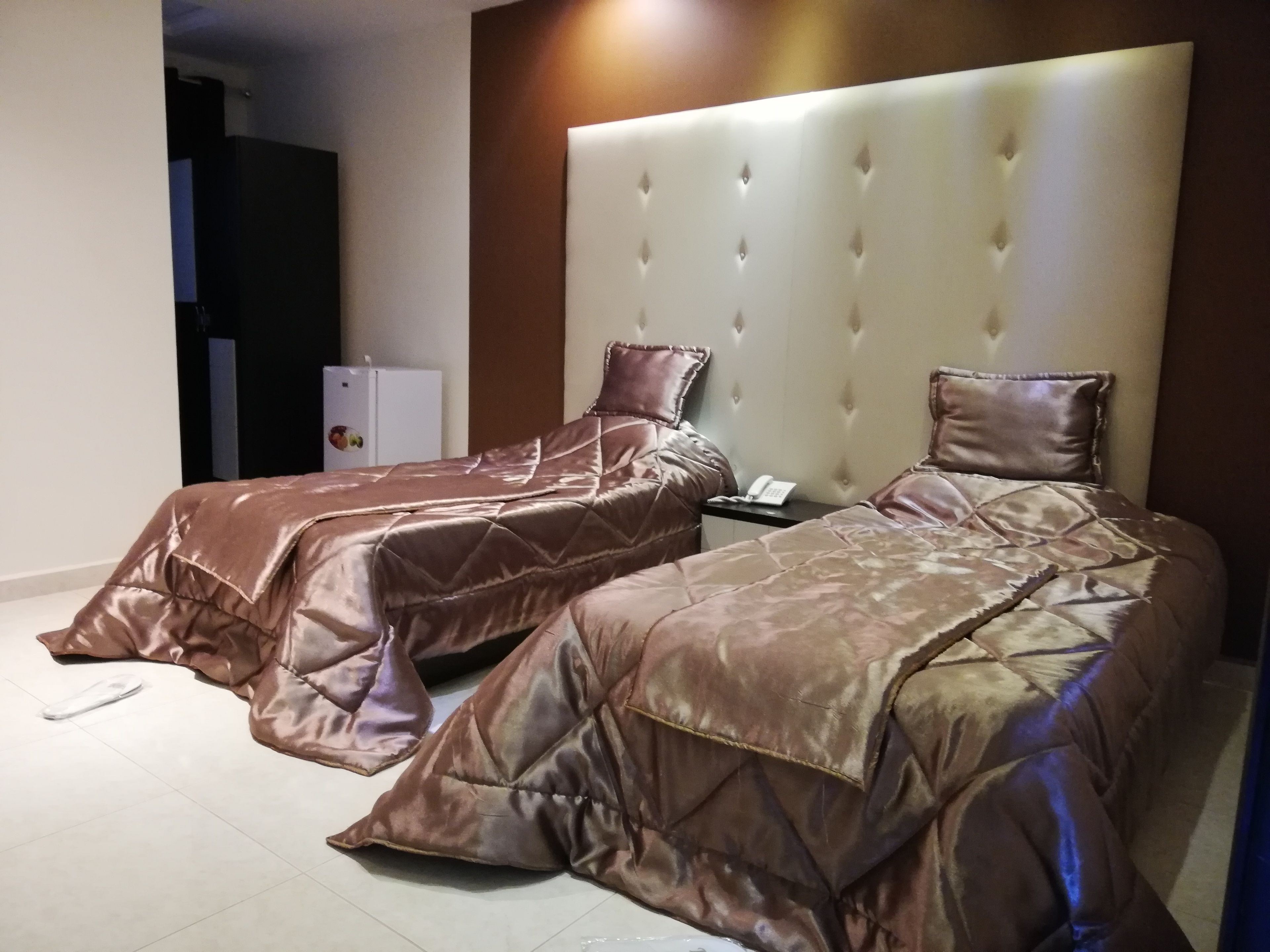 Habitación de hotel con dos camas, un minibar y un teléfono en la mesita de noche.