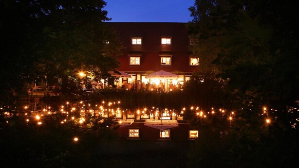 A two-story building with a large patio area in front, surrounded by trees. - Springbach-Mühle Belzig (Bad Belzig)