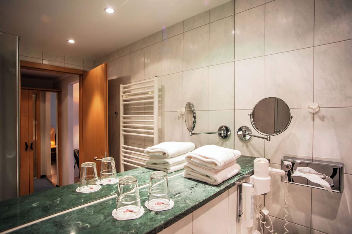 Un baño moderno con encimera de mármol, toallas apiladas, un secador de pelo y un espejo.