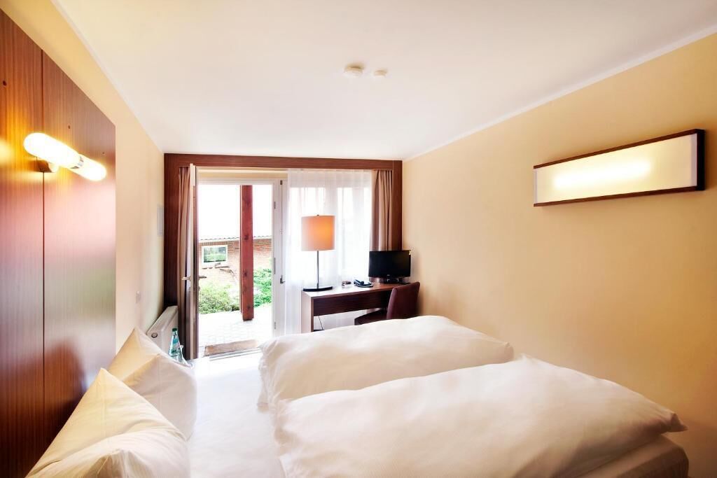 Una habitación de hotel con cama, escritorio, televisor y vistas al exterior.