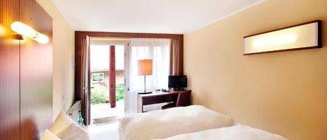Una habitación de hotel con cama, escritorio, televisor y vistas al exterior.