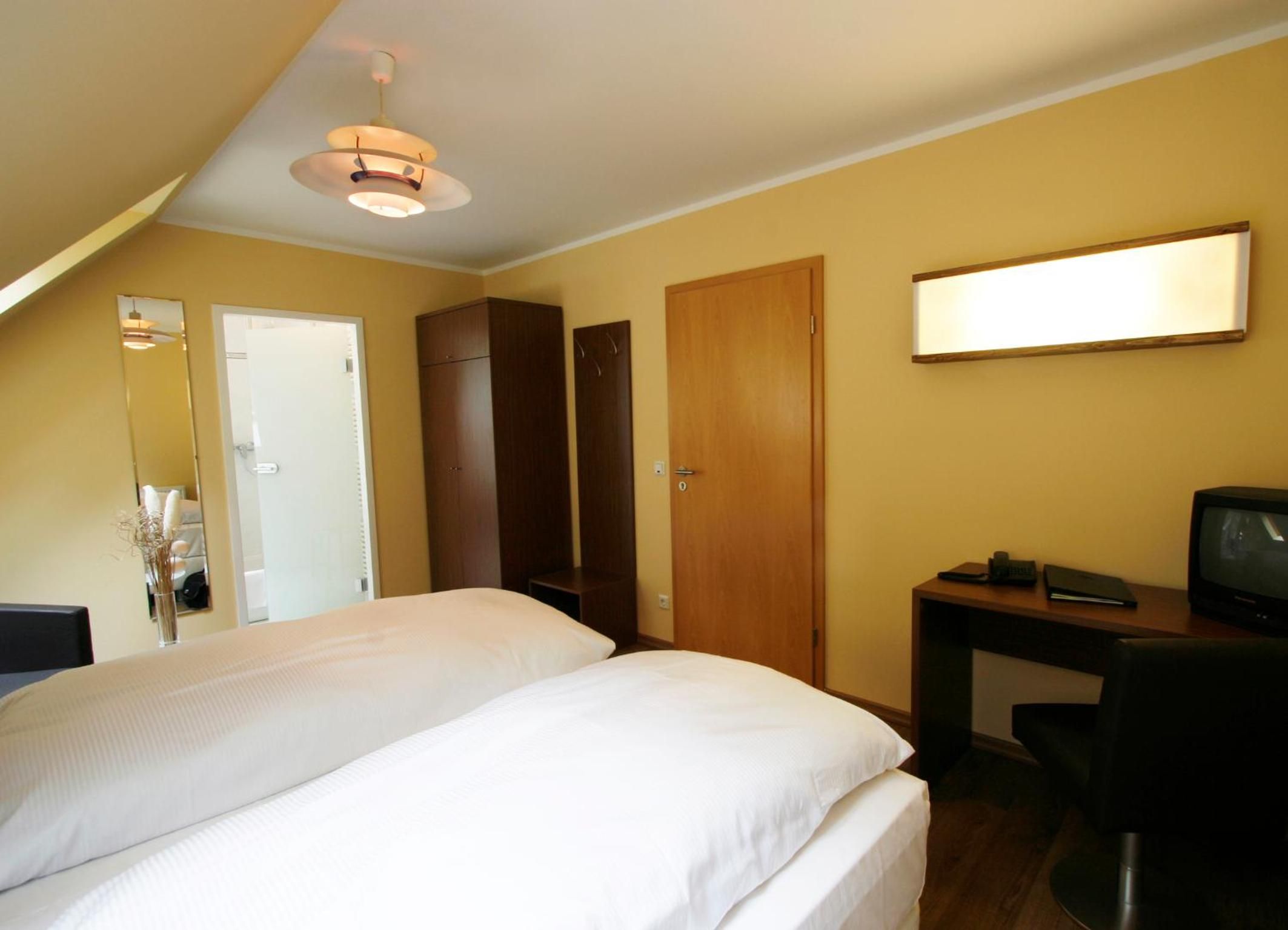 Una habitación de hotel con una cama, un escritorio, un televisor y un armario.