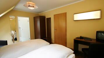 Una habitación de hotel con una cama, un escritorio, un televisor y un armario.