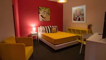 Ein modernes Schlafzimmer mit Bett, gelbem Sessel, Nachttisch und Schreibtisch mit Stuhl.