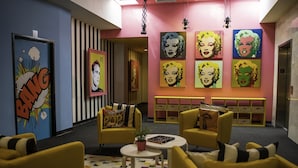 A lobby with yellow armchairs, a checkered floor, and pop art on the walls. - The Fox Hotel (Ponce)