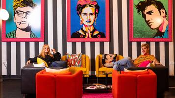A modern lounge area with striped walls, two sofas, a coffee table, and three framed artworks.