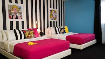 Een hotelkamer met twee bedden, behang met zwart-wit strepen en pop art prints aan de muur.