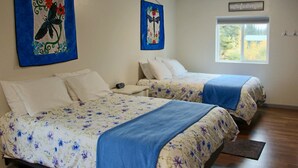 A bedroom with two beds, floral bedding, a window, and artwork on the walls. - Arctic Dragonfly Inn (Healy)