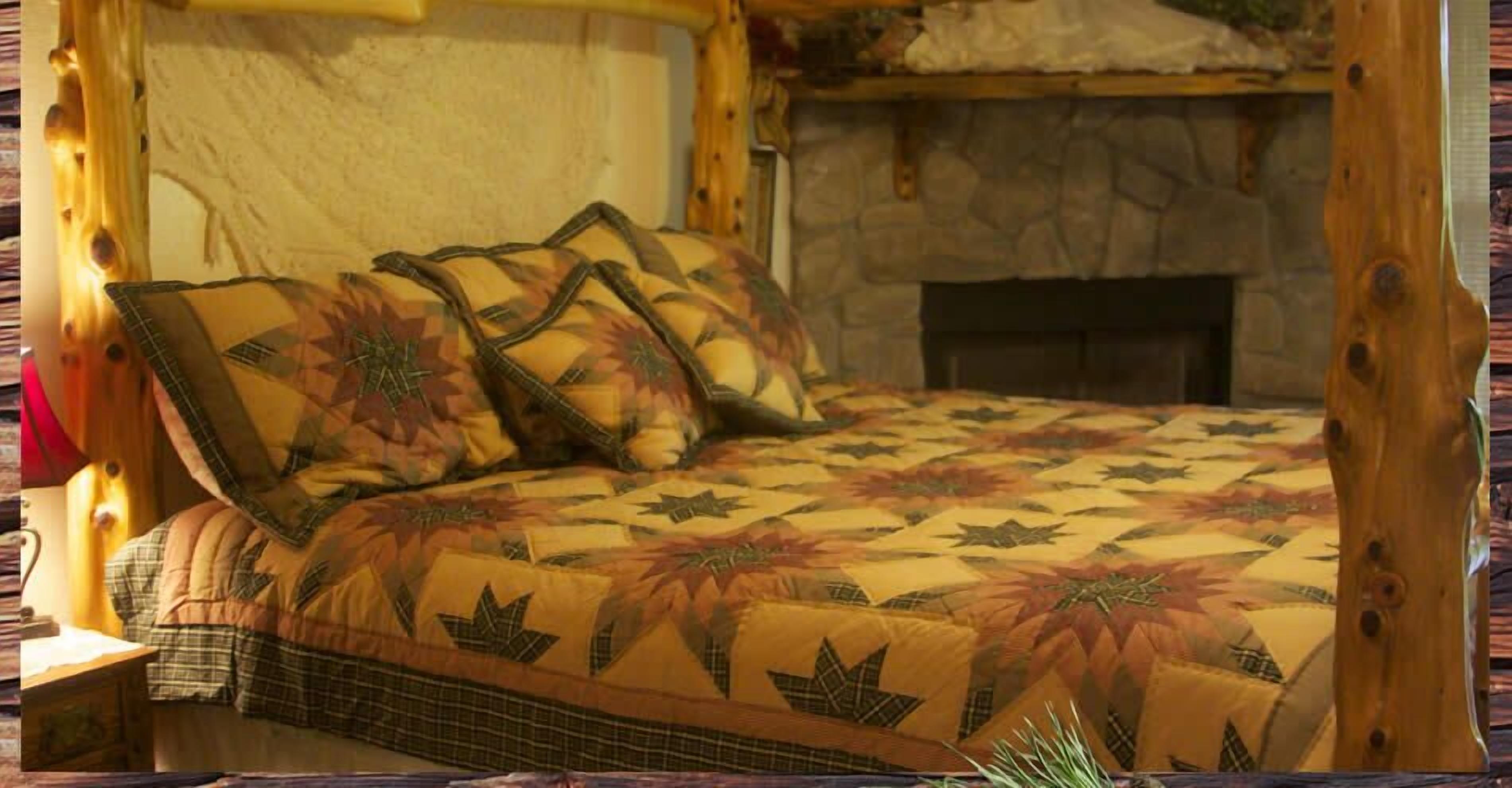 A bed with a floral patterned bedspread, a stone fireplace, and wooden beams.