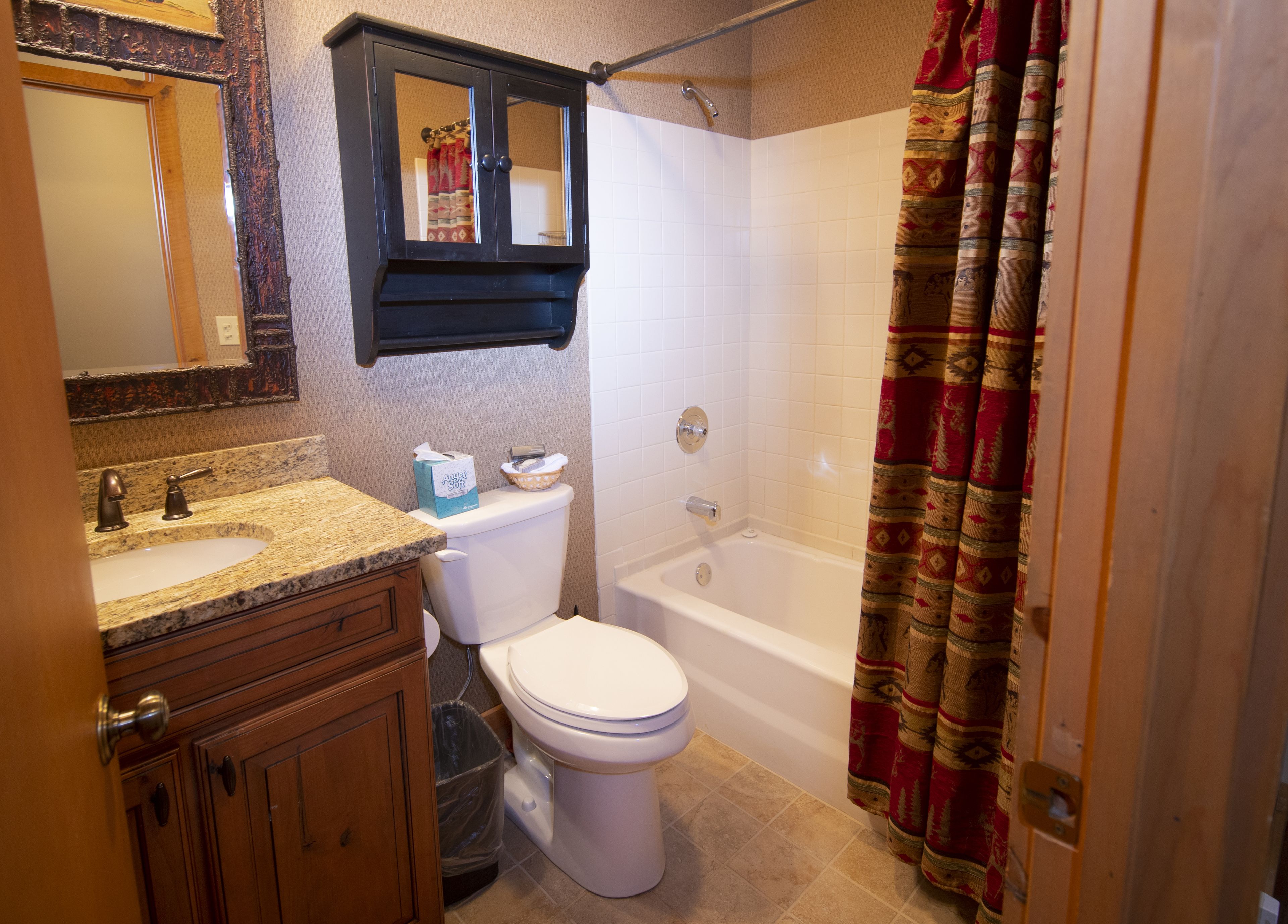 Een badkamer met toilet, wastafel, wastafelmeubel en bad.