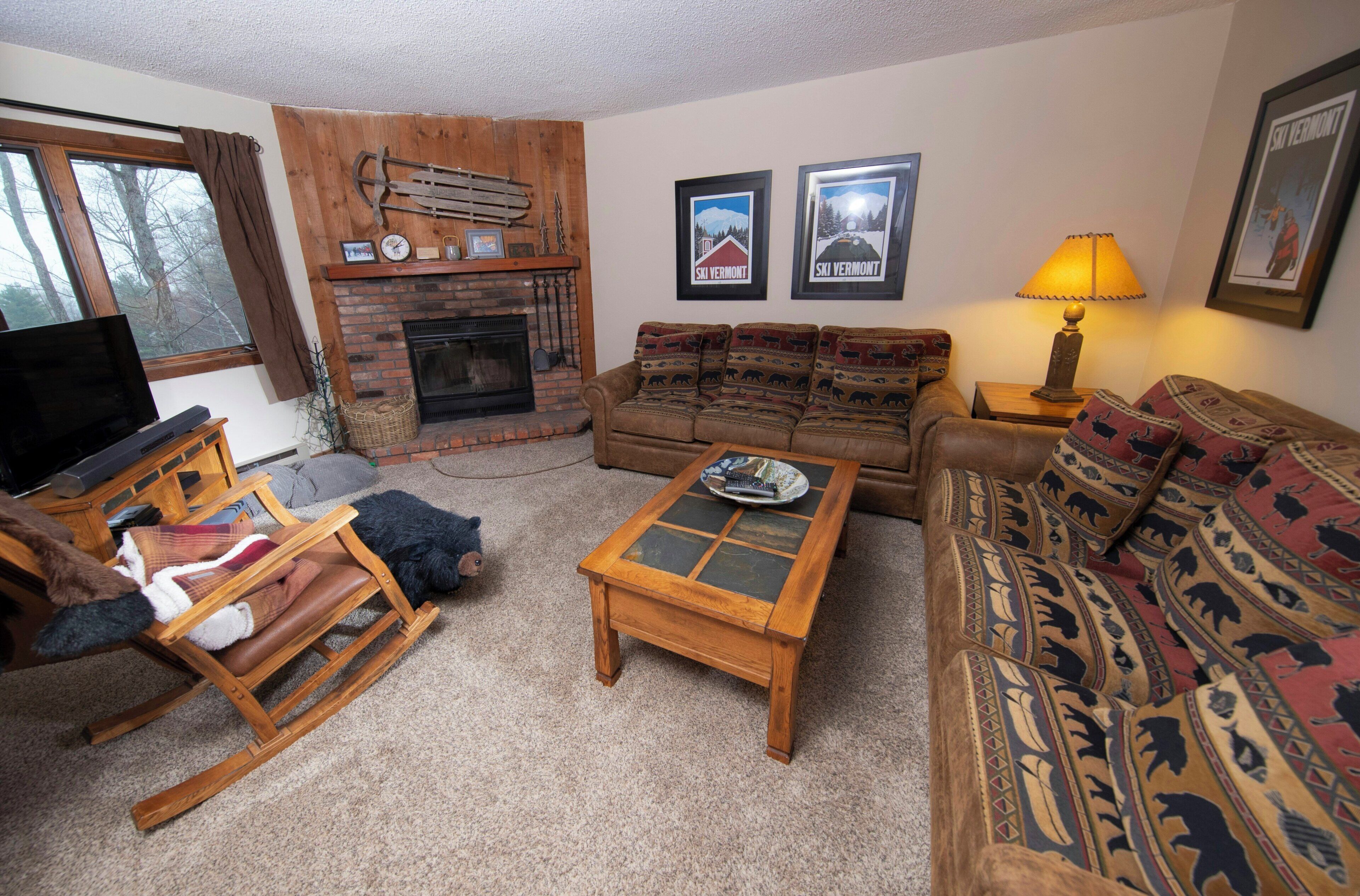 A cozy living room with a fireplace, a sofa set, a coffee table, and a television.