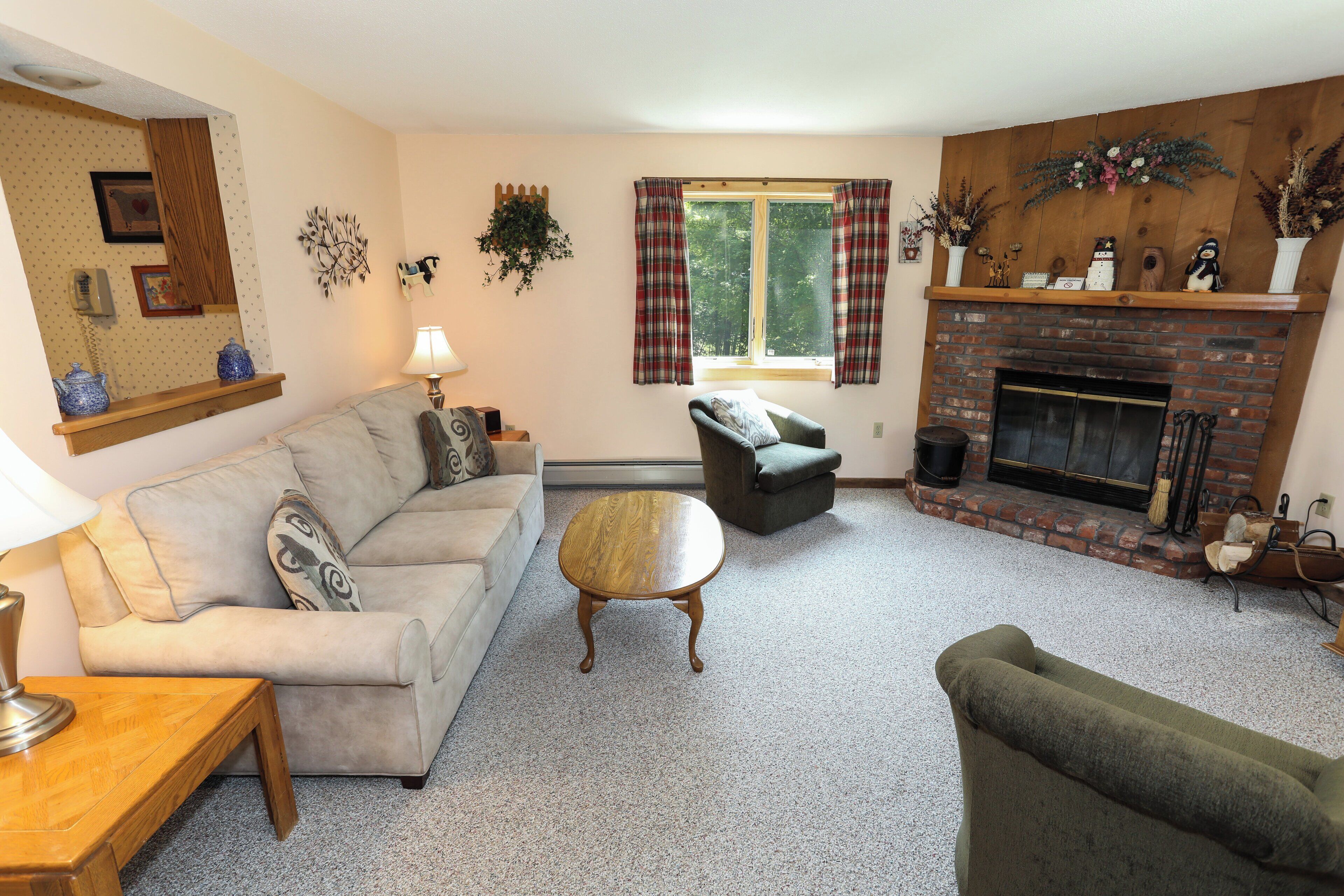 A cozy living room with a fireplace, a sofa, a coffee table, and a chair.