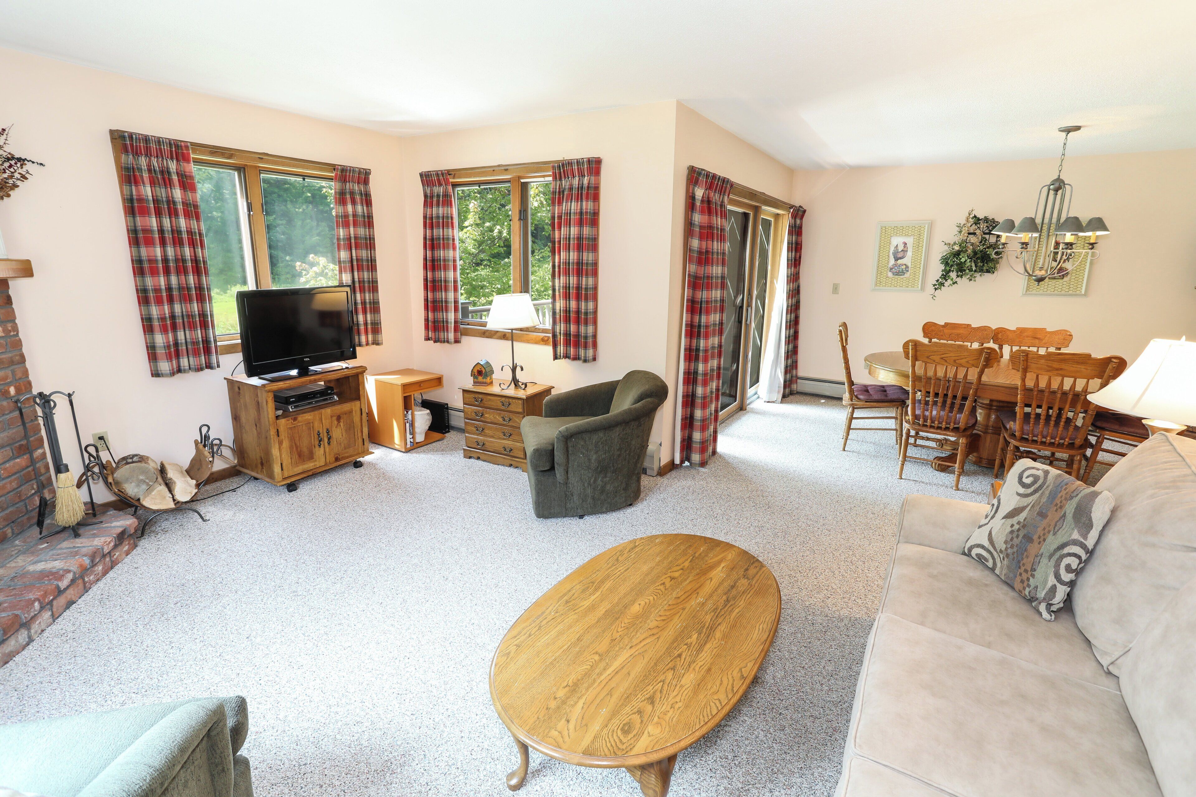 A living room with a television, sofa, coffee table, and dining area.