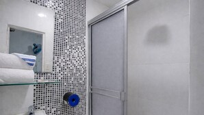 A bathroom with a white sink, a glass shelf, a toilet, and a shower area. - Quillahost Guesthouse (Barranquilla)