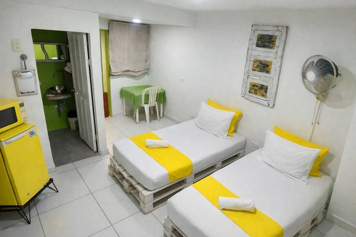 A hotel room with two beds, a microwave, a sink, and a fan.