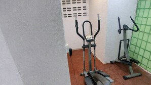 A gym with two elliptical machines and a wall-mounted exercise bike.