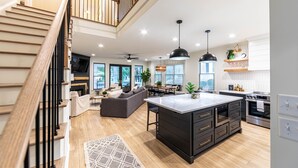 A modern kitchen with a central island, wooden flooring, and pendant lighting. - Pet friendly Reynolds Lake Oconee Retreat with Common Areas and Dock Access. (Greensboro)