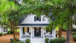 A white house with a front porch, surrounded by trees and shrubs. - Pet friendly Reynolds Lake Oconee Retreat with Common Areas and Dock Access. (Greensboro)