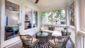 A covered porch with wicker furniture, a round glass table, and a ceiling fan. - Pet friendly Reynolds Lake Oconee Retreat with Common Areas and Dock Access. (Greensboro)