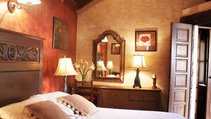 Une chambre à coucher avec un grand lit, deux lampes de chevet, une commode, un miroir et une porte.