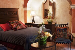 Ein Hotelzimmer mit Bett, Stuhl, Tisch, Lampe und Spiegel.