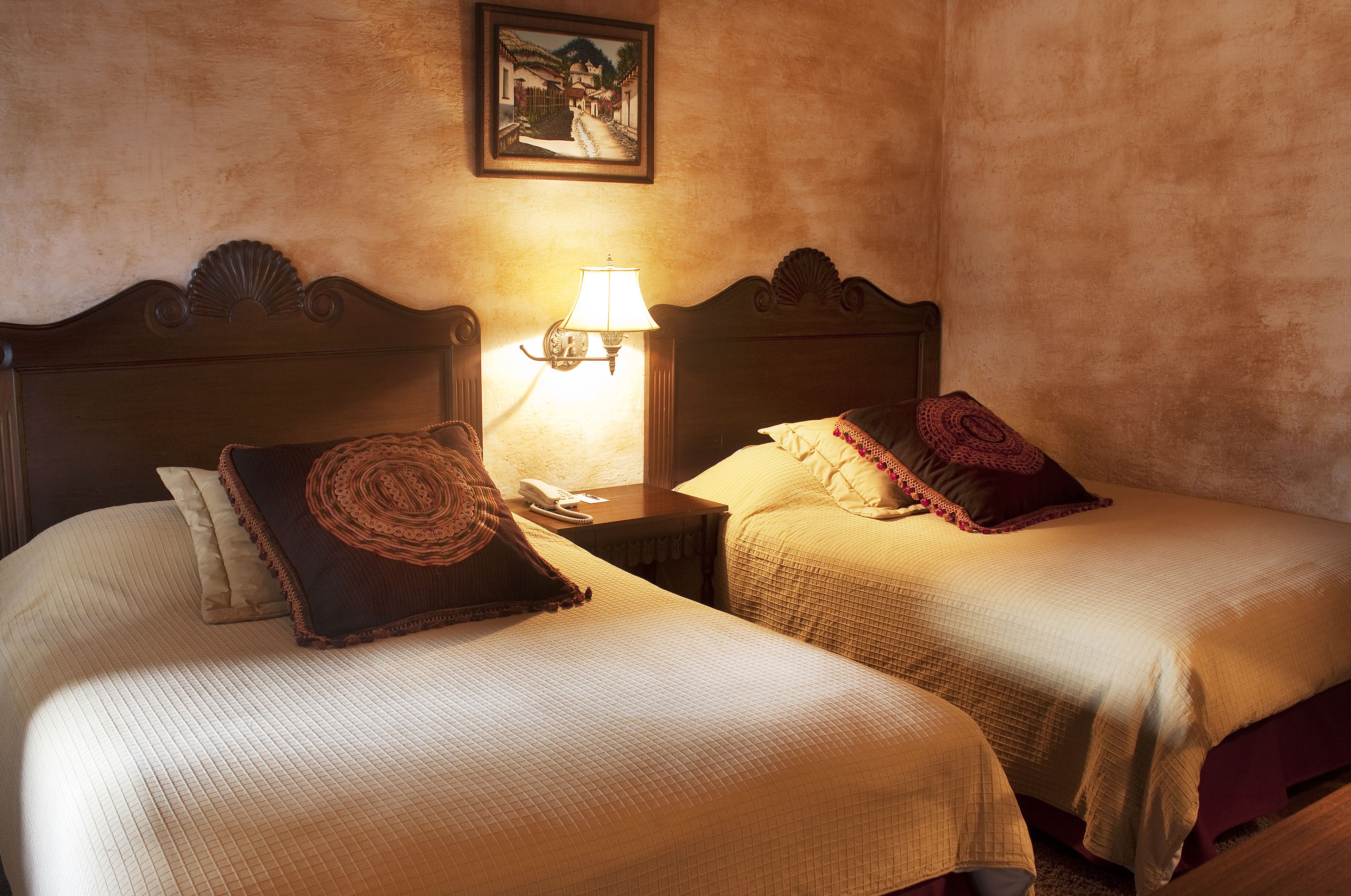Two beds with headboards, a bedside lamp, and a framed picture on the wall.