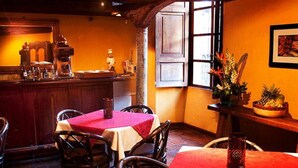 Un interior de restaurant acollidor amb taules i cadires de fusta, una zona de bar i un gran finestral amb vistes.