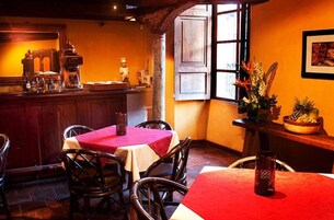 Un acogedor interior de restaurante con mesas y sillas de madera, una zona de bar y un amplio ventanal con vistas.