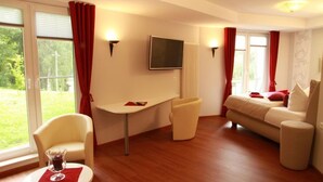A modern hotel room with a bed, a desk, a chair, and a TV. - Waldhaus Lauenhain (Mittweida)