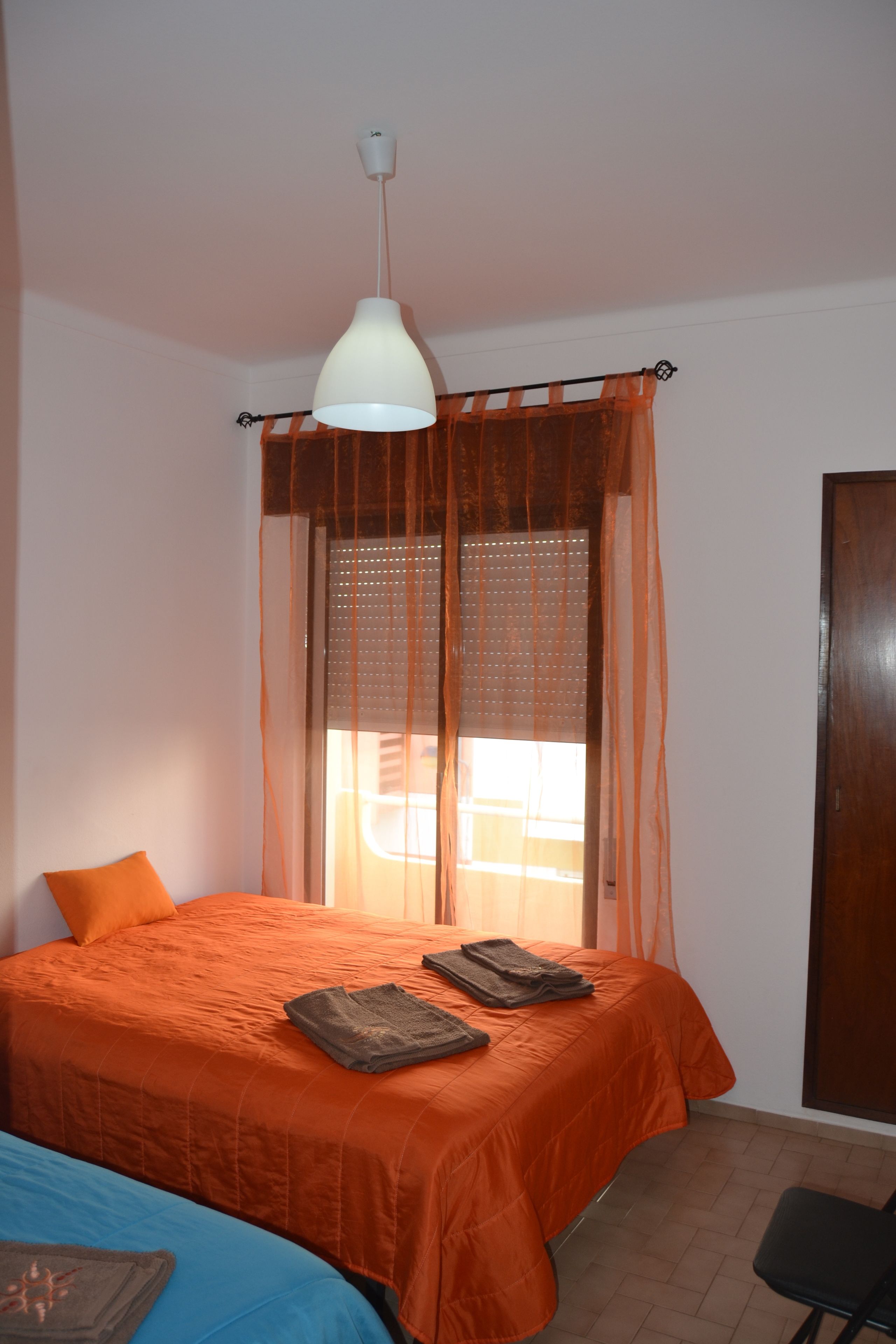 Une chambre à coucher avec un lit, une chaise, une fenêtre avec des rideaux et une porte.