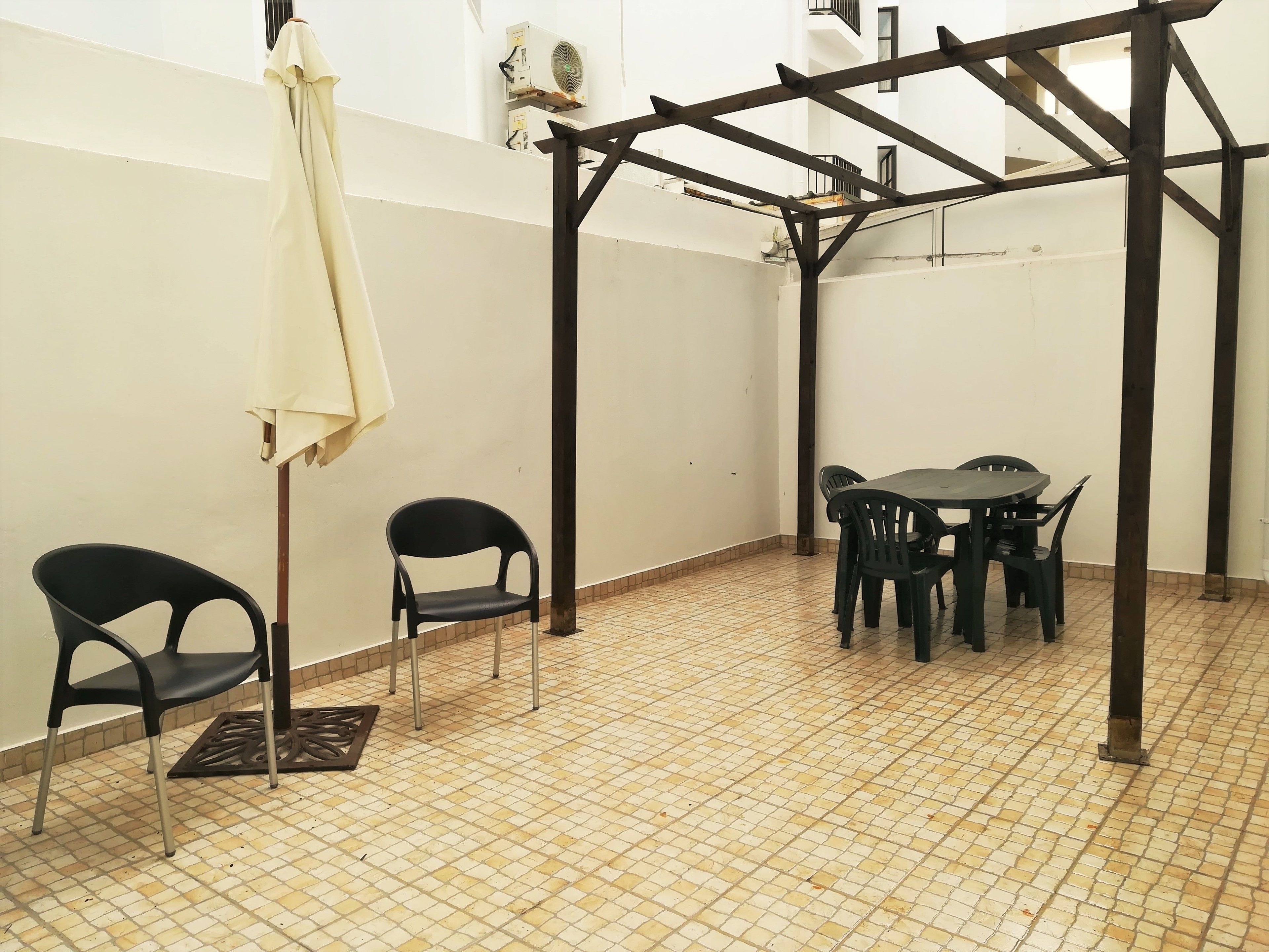 Une pièce avec un sol carrelé, une table entourée de chaises et un ventilateur de plafond.
