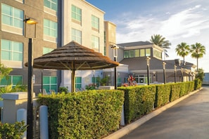 Un hotel de diseño moderno, con un área de estar exterior techada y un seto cuidado a lo largo del camino.