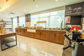 A modern kitchen with a marble countertop, wooden cabinets, and a coffee station. - Holiday Inn Historic (St. Augustine)