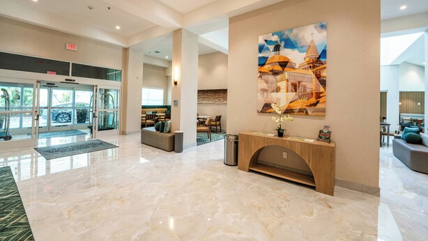 A spacious lobby with a marble floor, a reception desk, a large wall art piece, and a seating area with a view of the outdoors. - Holiday Inn Historic (St. Augustine)
