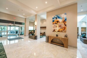 A spacious lobby with a marble floor, a reception desk, a large wall art piece, and a seating area with a view of the outdoors. - Holiday Inn Historic (St. Augustine)