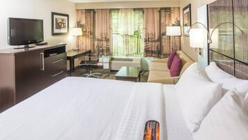 A hotel room with a bed, a desk, a chair, a television, and a window with curtains.