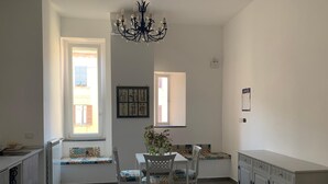A bright kitchen with a dining table, chairs, a chandelier, and a window with a view of buildings. - Specchio di Parthenope (Naples)