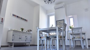 A dining area with white furniture, a chandelier, and artwork on the walls. - Specchio di Parthenope (Naples)