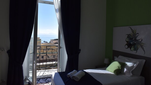 A hotel room with a bed, a view of the balcony, and a green wall. - Specchio di Parthenope (Naples)